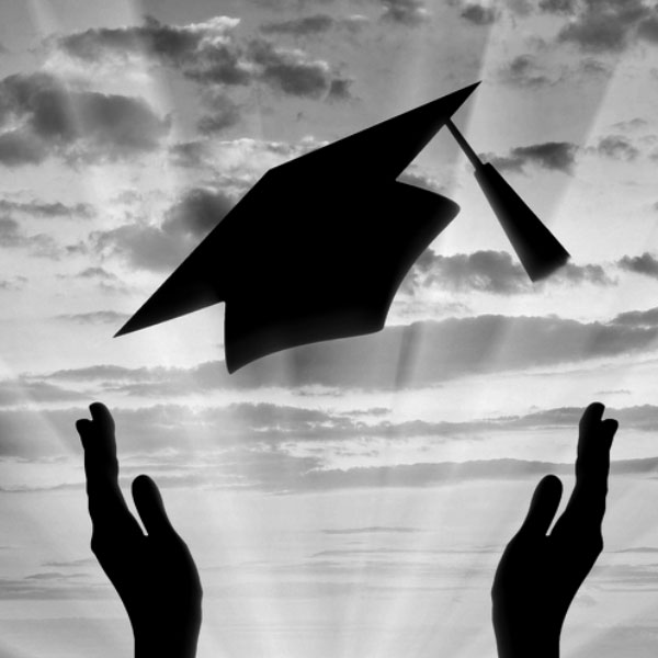 black and white image of a person throwing their graduation cap in the air.
