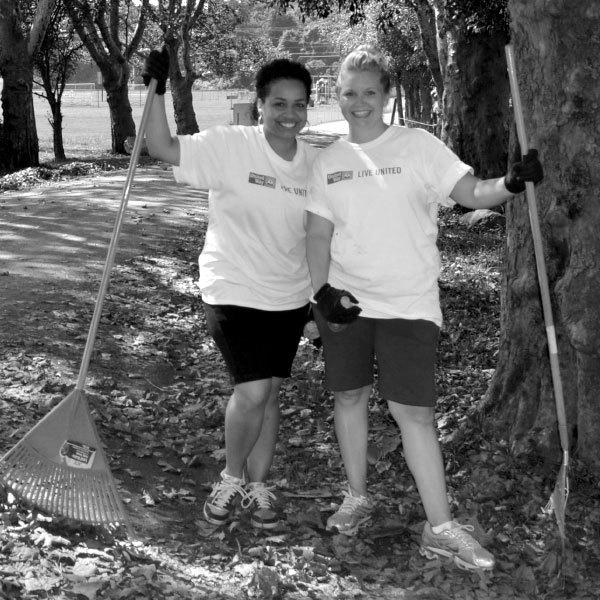 Black and white image of two Diamond members raking leaves to serve their community.